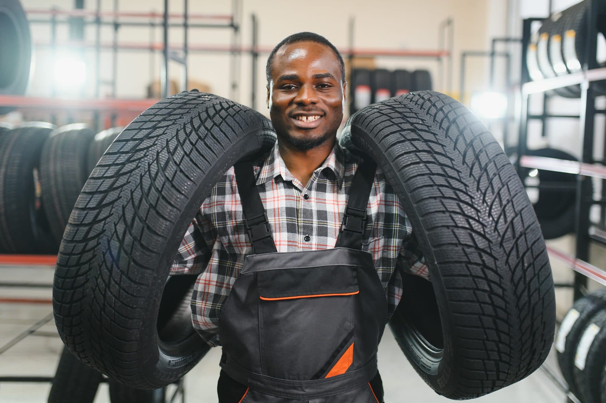 A technician carrying two new tyres